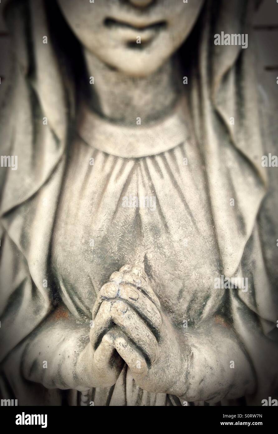 Una statua di una donna con mani giunte in preghiera. Foto Stock