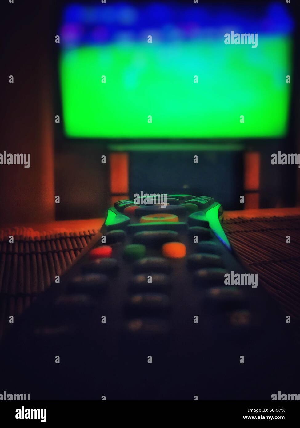 Una televisione / tv via cavo remoto nella parte anteriore di un televisore che mostra lo sport. - Immagine stock catturata con smartphone