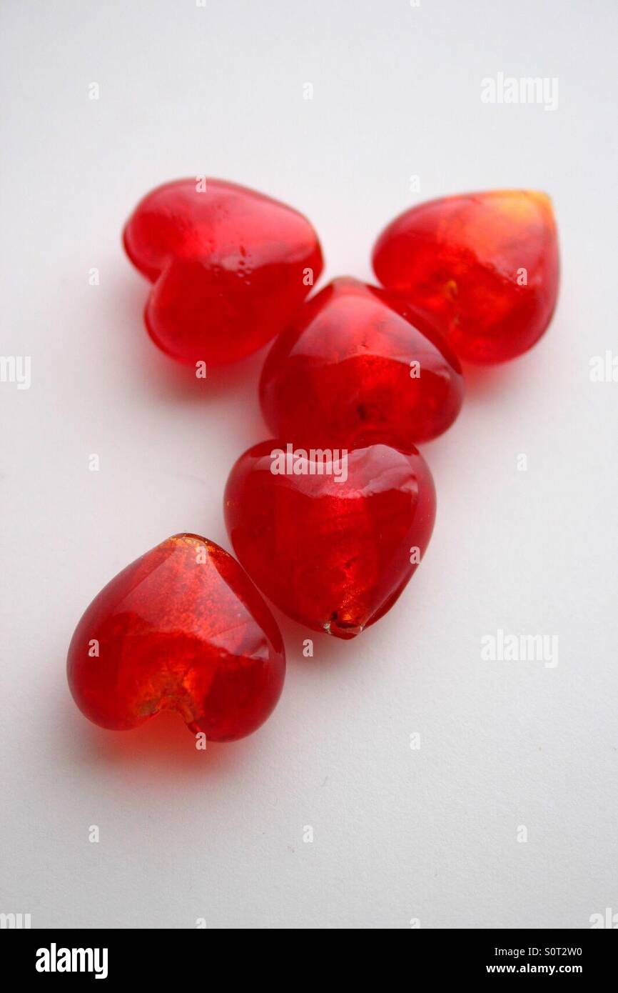 Rosso profondo di vetro a forma di cuore i talloni su uno sfondo bianco. Foto Stock