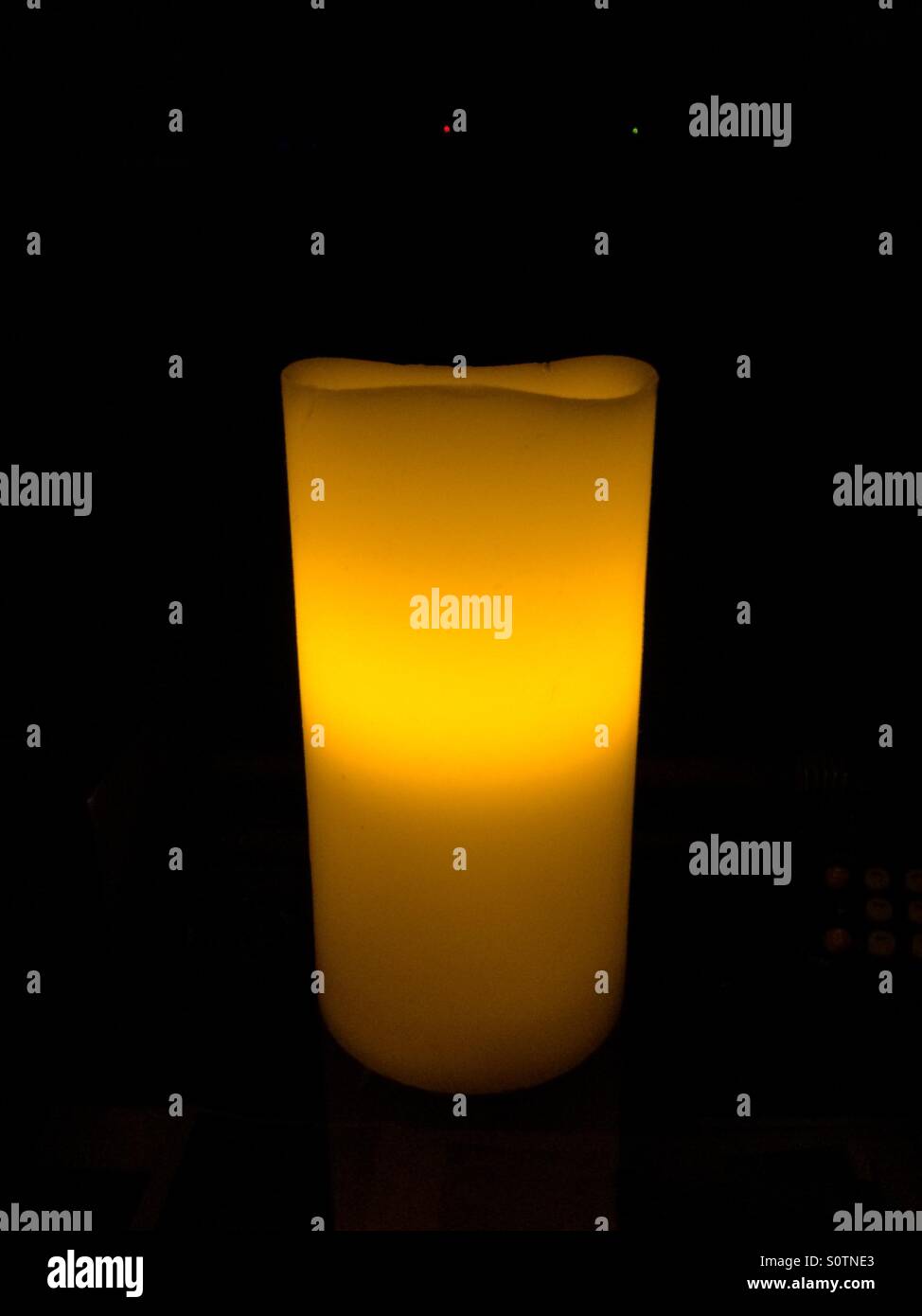 Una candela accesa in una stanza buia. Foto Stock