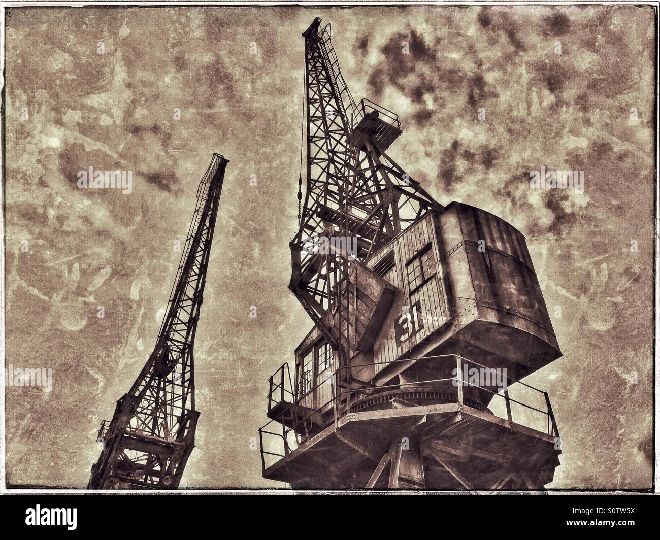 Due delle gru situato sul bordo della Floating Harbour a Bristol, Inghilterra. Un effetto di grunge foto per illustrare il passare del tempo e un'era da molto tempo fa. Credito foto - © COLIN HOSKINS. - Immagine stock catturata con smartphone