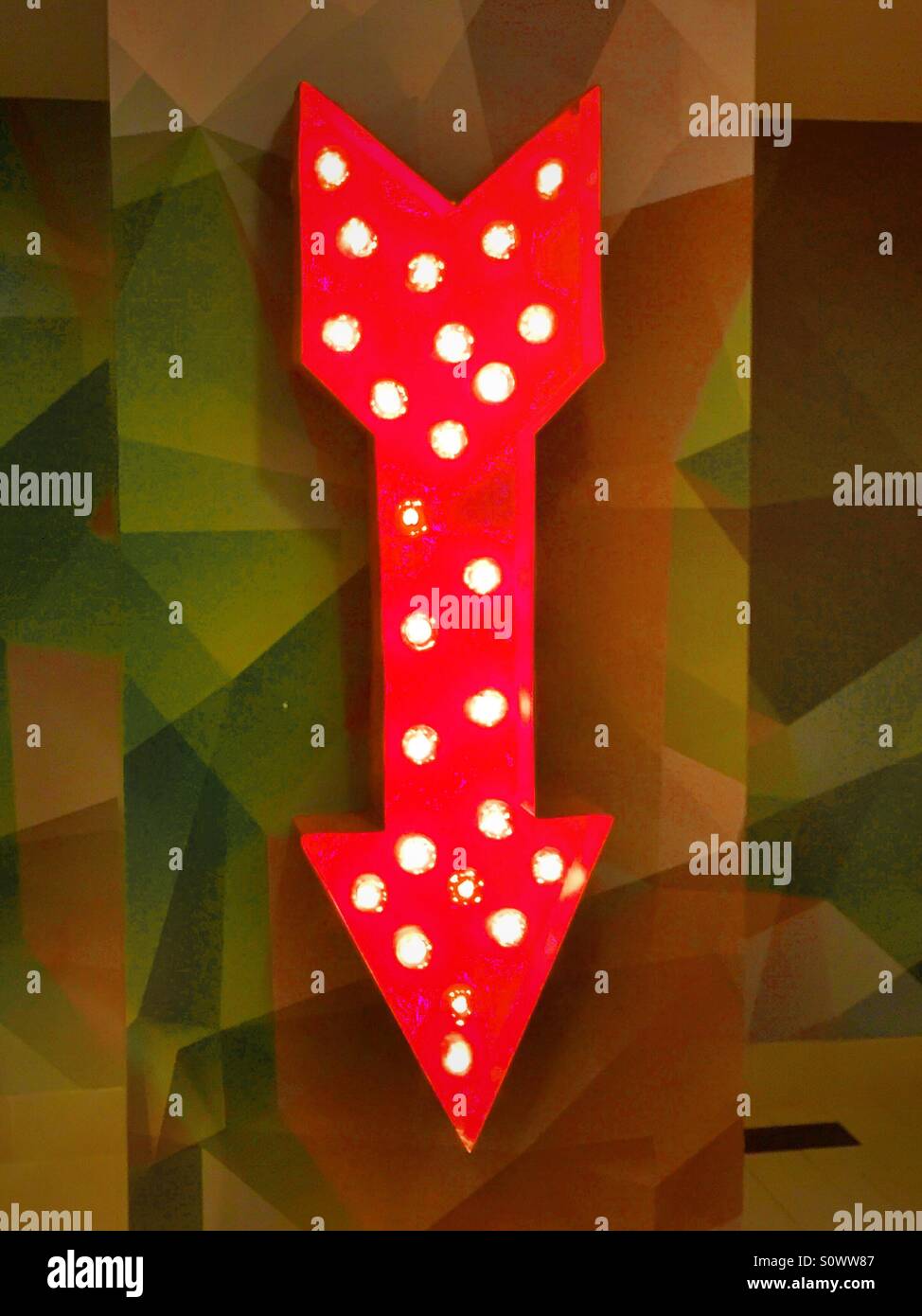 Illuminata luminosamente freccia rossa rivolta verso il basso - Immagine stock catturata con smartphone