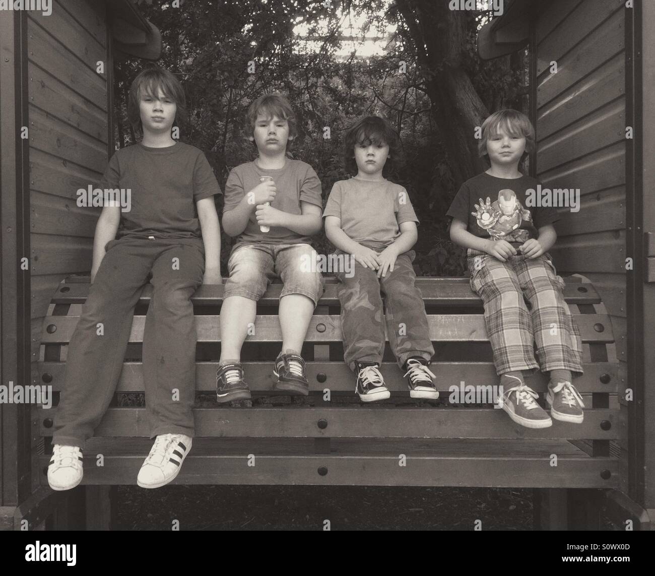 Quattro ragazzi da 3 a 8 anni di seduta - Immagine stock catturata con smartphone