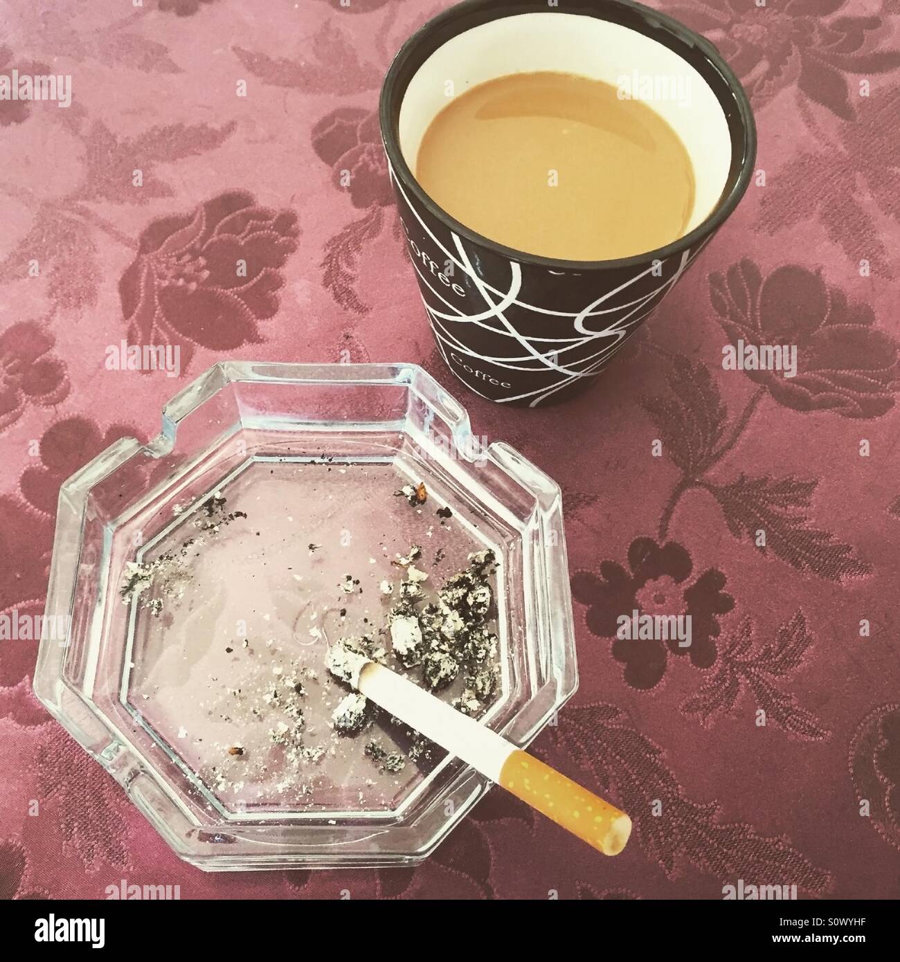 Caffè e sigarette in posacenere sul tavolo vista superiore Foto Stock
