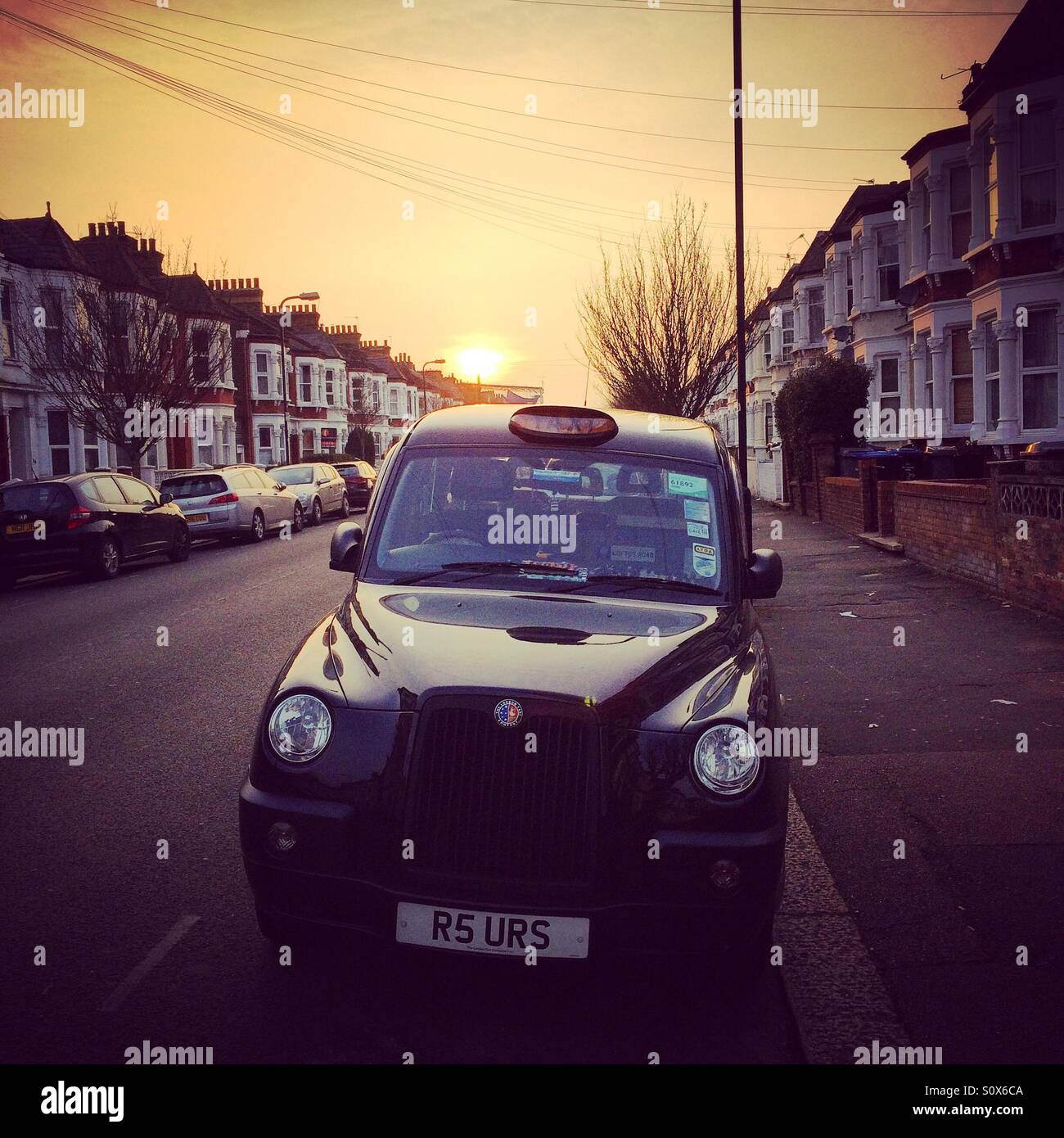 Il sole tramonta dietro un taxi nella zona ovest di Londra Foto Stock