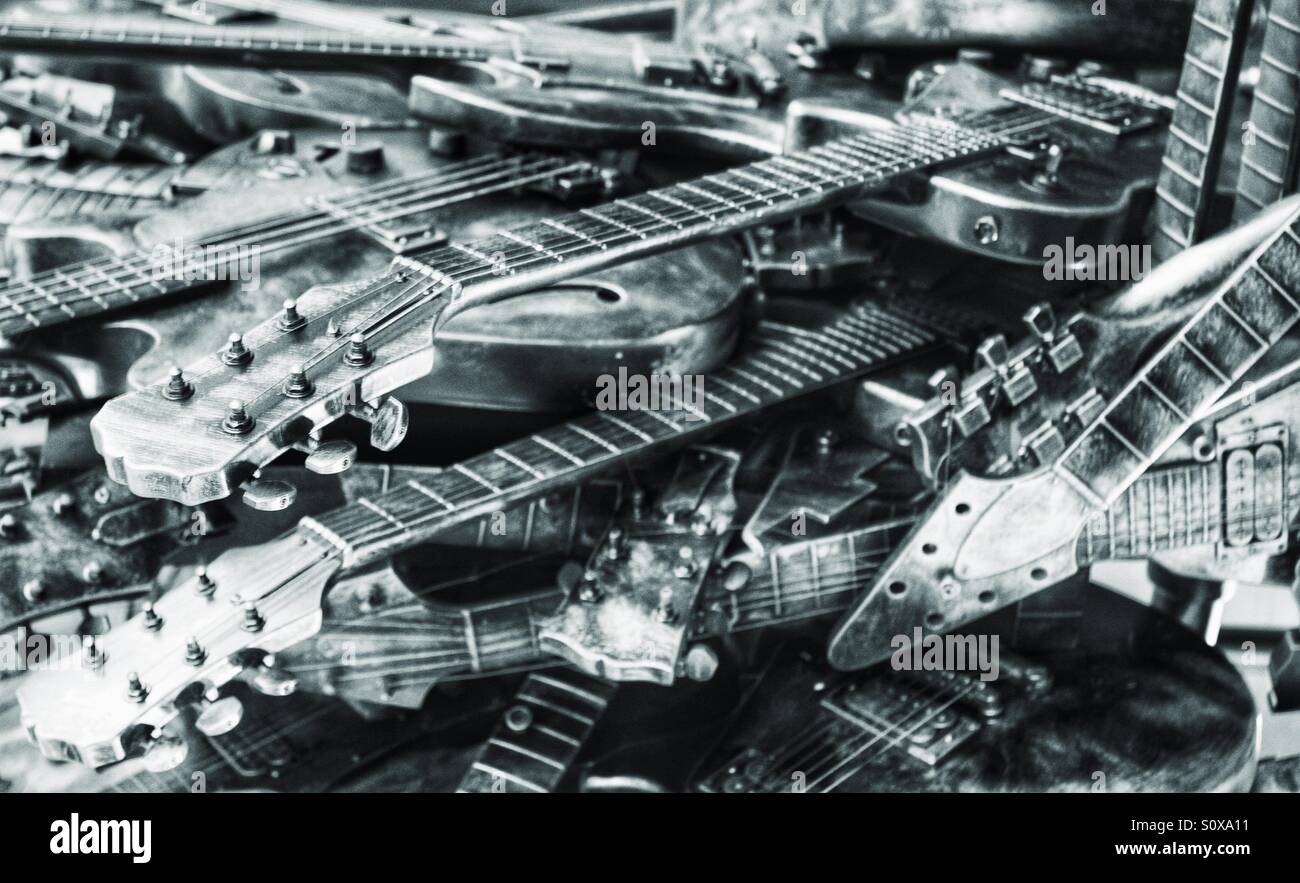 Scartato chitarre in un mucchio disordinato. Immagine in bianco e nero con una finitura metallica. Un sacco di chitarre. - Immagine stock catturata con smartphone