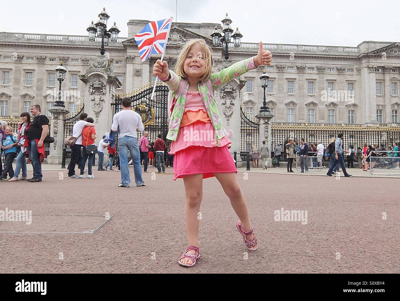 Una giovane ragazza pone fuori Buckingham Palace a Londra Foto Stock
