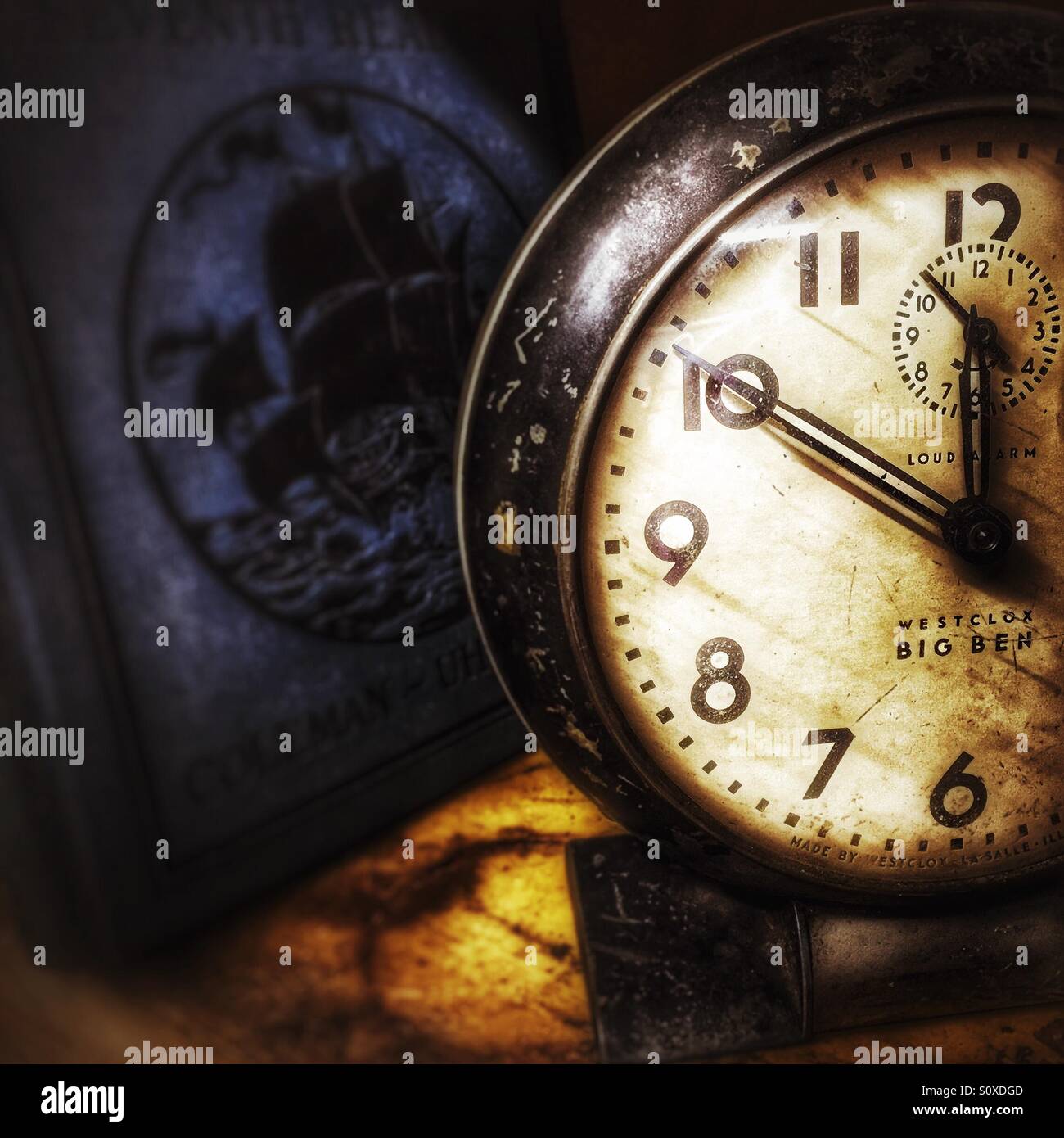 Orologio vintage su uno scaffale con vecchio libro sullo sfondo - Immagine stock catturata con smartphone