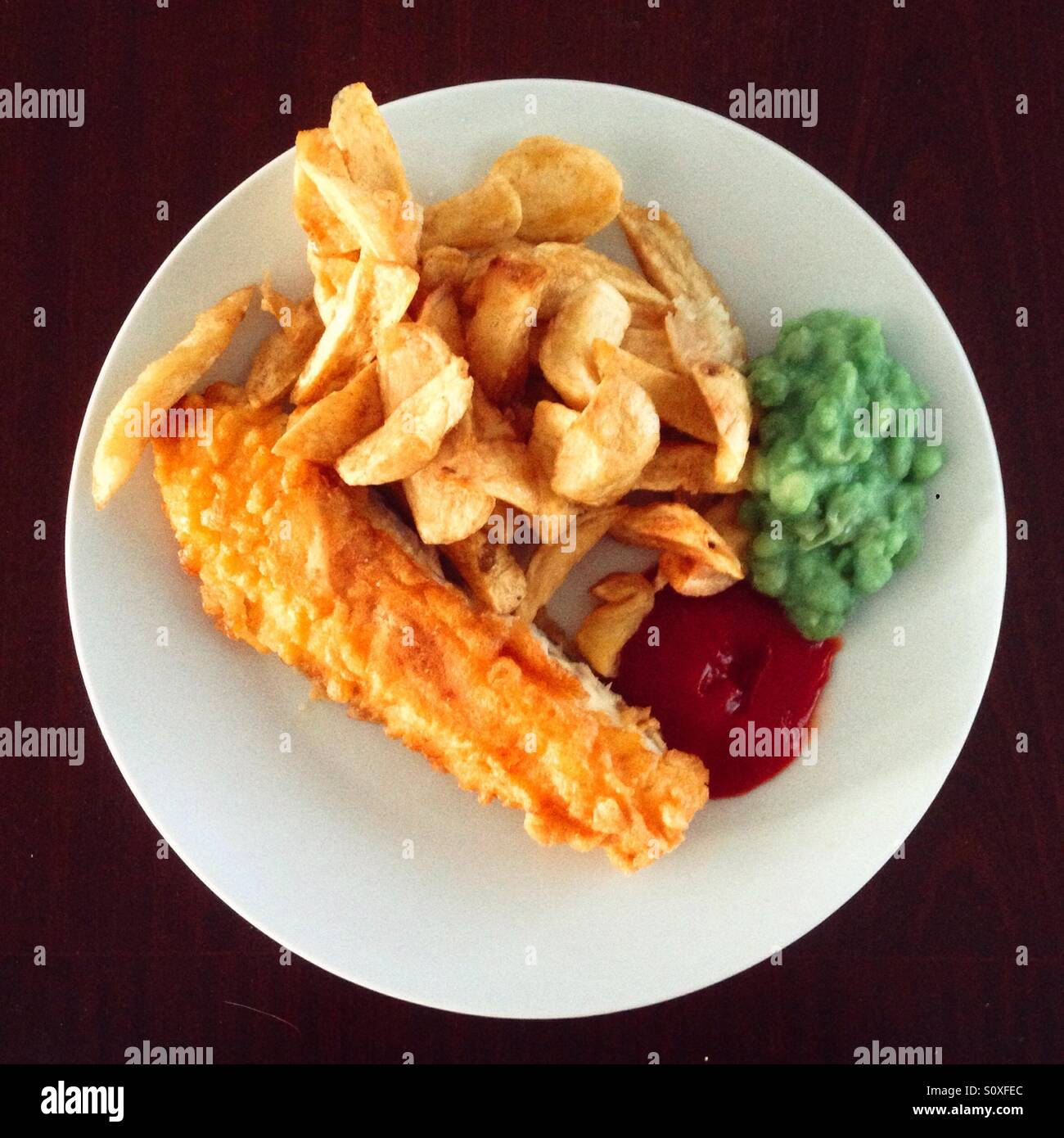 Piastra di inglese tradizionale pesce e patatine con fiacco di piselli e salsa di pomodoro. Foto Stock