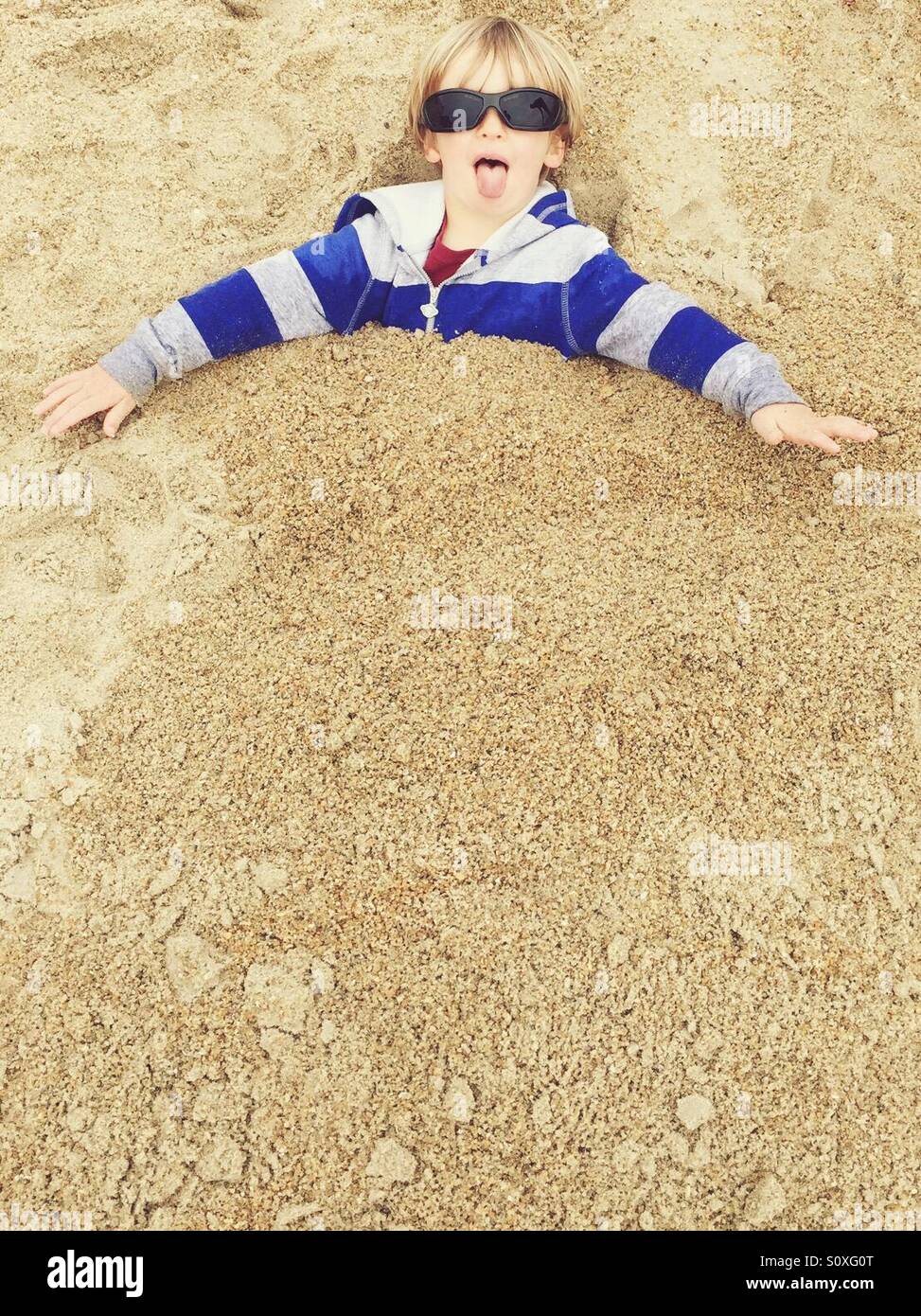 Ragazzo carino sepolto nella sabbia Foto Stock