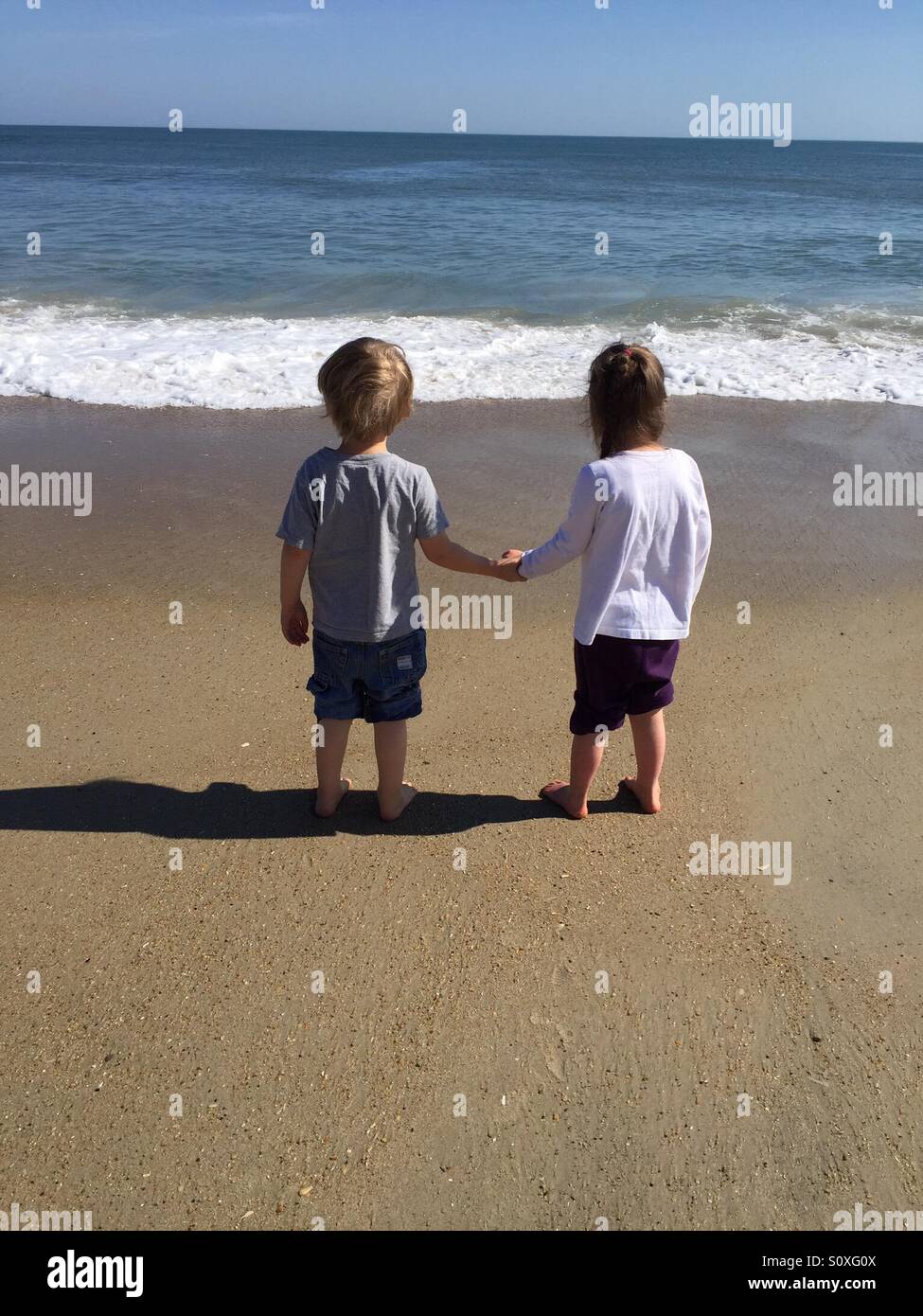 Un ragazzo e una ragazza tenendo le mani sulla spiaggia Foto Stock