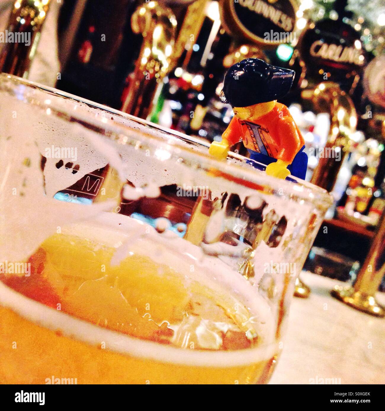 Una figura di Lego bere pale ale birra da una pinta di vetro in un pub Inglese con rubinetti in background Foto Stock