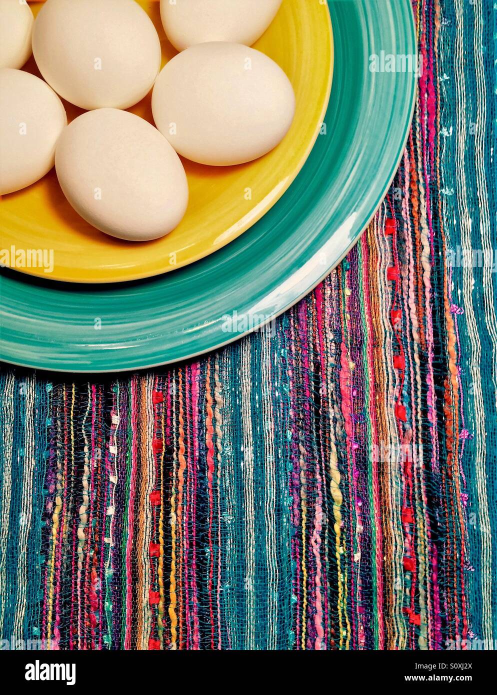 Bianco uova intere su una piastra colorata e la tovaglia visto dal di sopra - Immagine stock catturata con smartphone