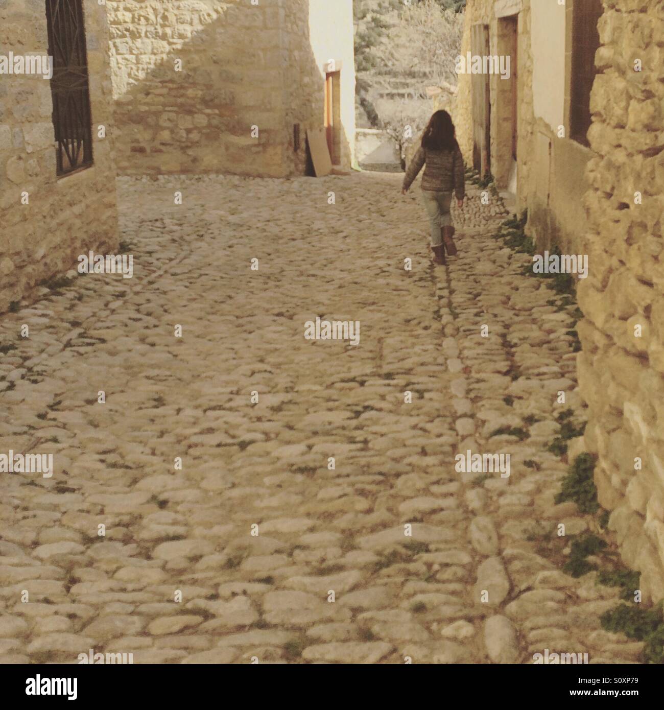 Ragazza a piedi in una strada vuota nel vecchio villaggio di Mirambel, nella provincia di Teruel, Spagna Foto Stock