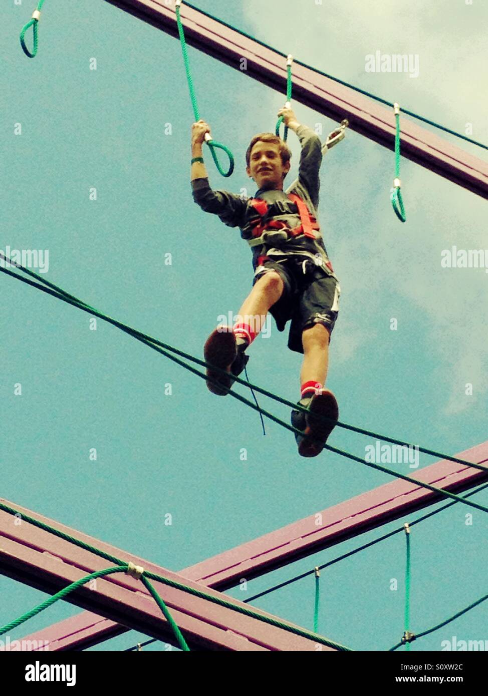 Ragazzo di arrampicarsi su un corso di funi Foto Stock