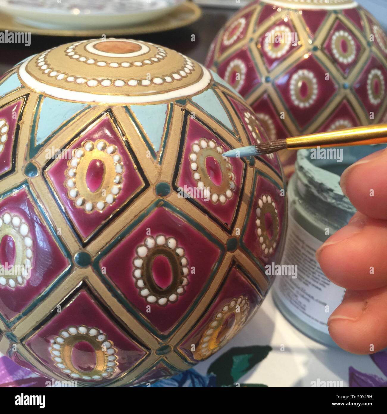 Un primo piano di qualcuno di verniciatura di un progetto su una sfera di ceramica. Foto Stock