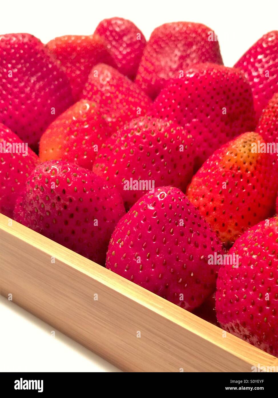 Fragole fresche in un vassoio di legno con sfondo bianco - Immagine stock catturata con smartphone