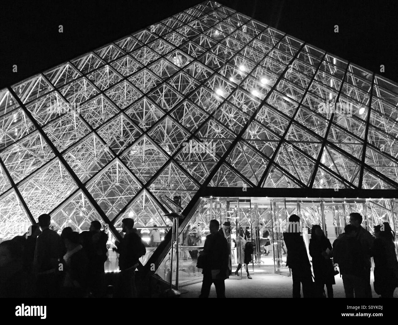 Sagome di persone stand al di fuori della classe piramide del Louvre di Parigi. Foto Stock