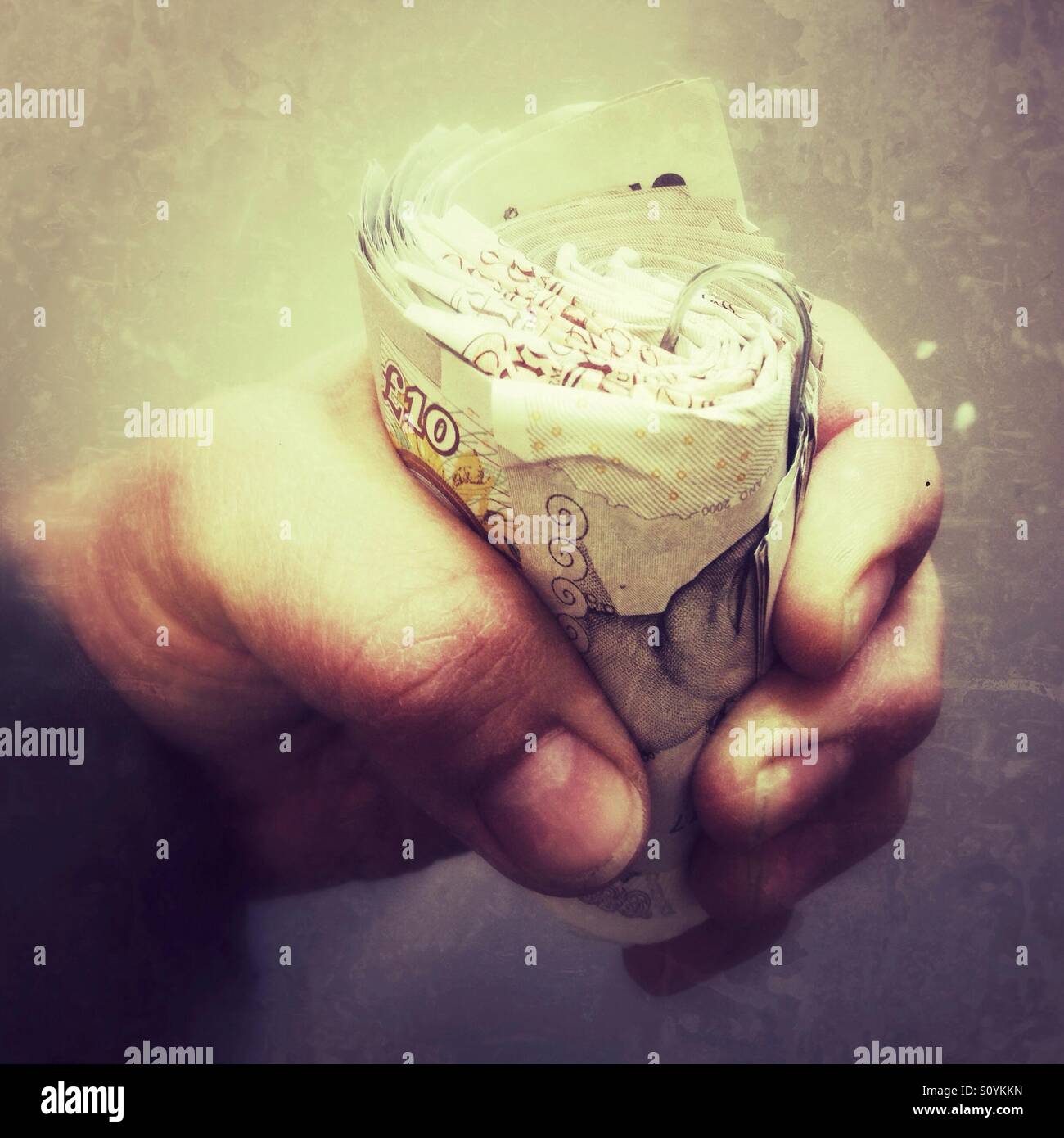 Mille libbre in dieci pound note afferrato in un rotolo. - Immagine stock catturata con smartphone