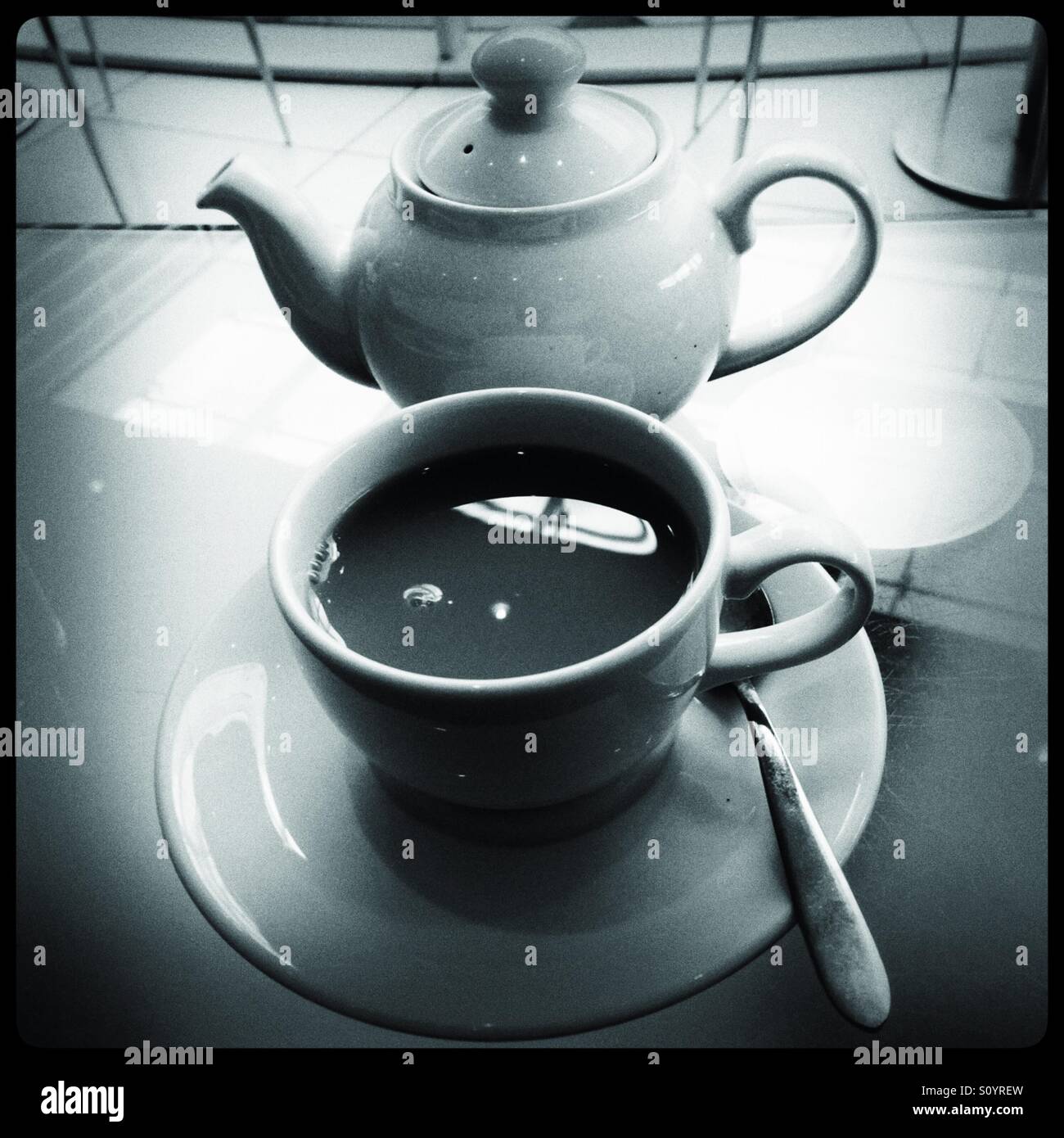 Tazza di tè e teiera sul tavolo di vetro - Immagine stock catturata con smartphone