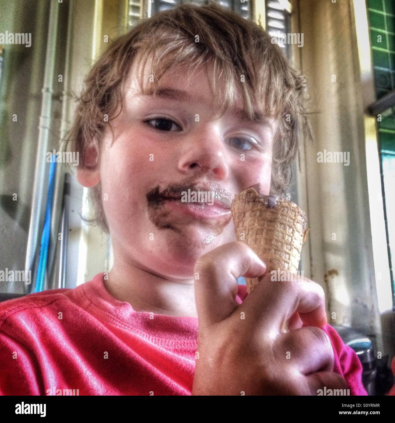 Ragazzo cinque anni di mangiare il gelato al cioccolato di cono Foto Stock