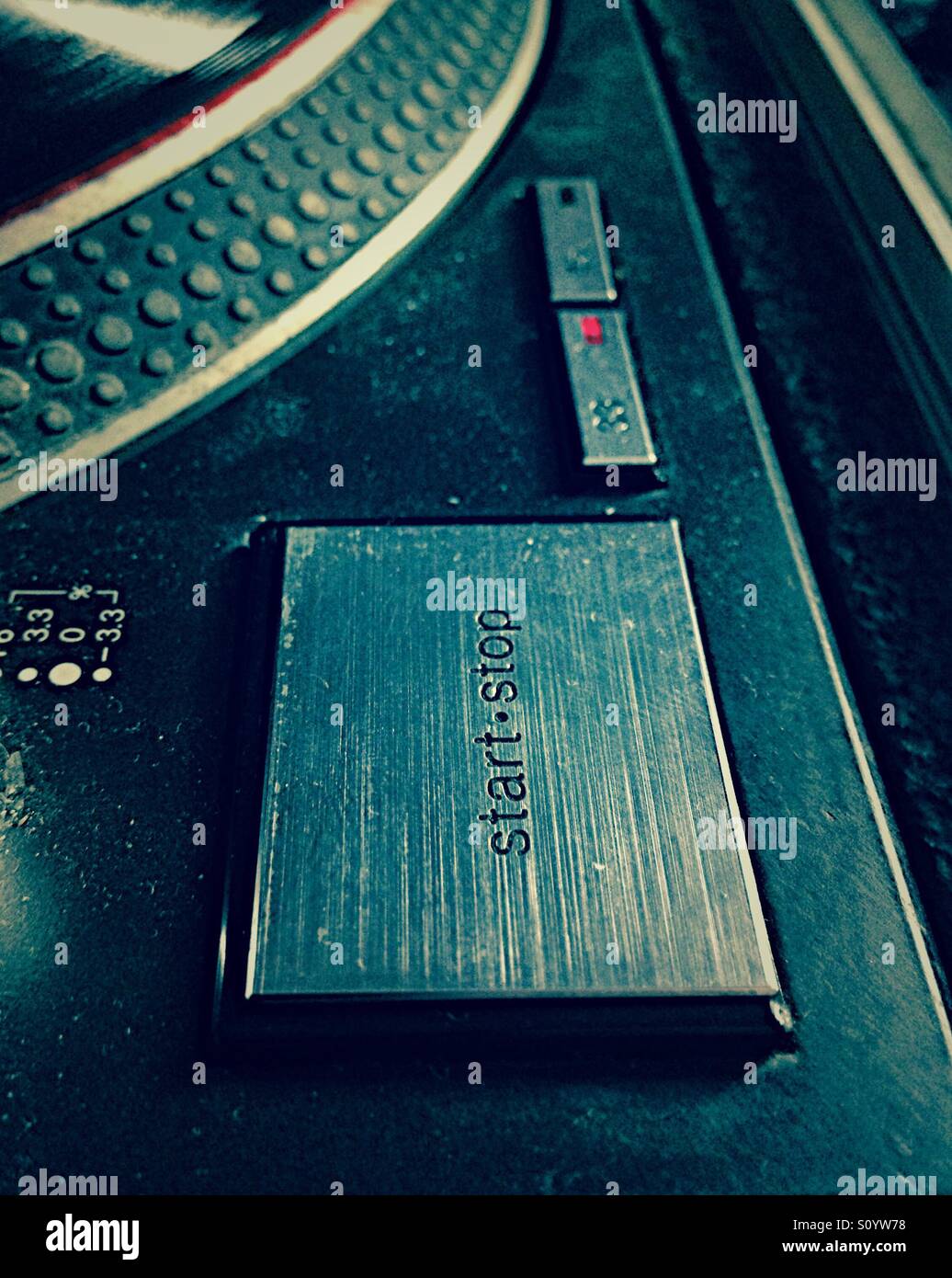 Close up 'Start Stop' pulsante su un usato pesantemente Technics SL-1210 DJ giradischi. Foto Stock