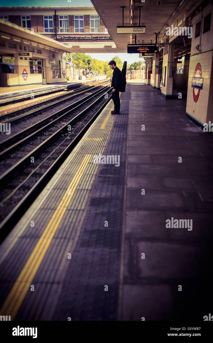 Lone chitarrista in attesa di un treno Foto Stock
