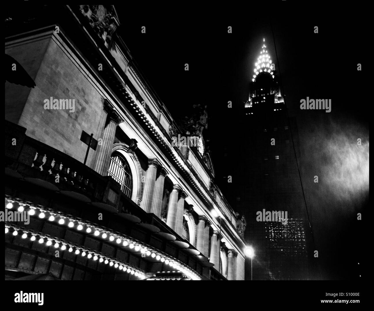 La Grand Central Station e il Chrysler Building illuminato in una piovosa notte di nebbia in bianco e nero di moody iPhoneography attrazioni di Manhattan a New York City. Foto Stock