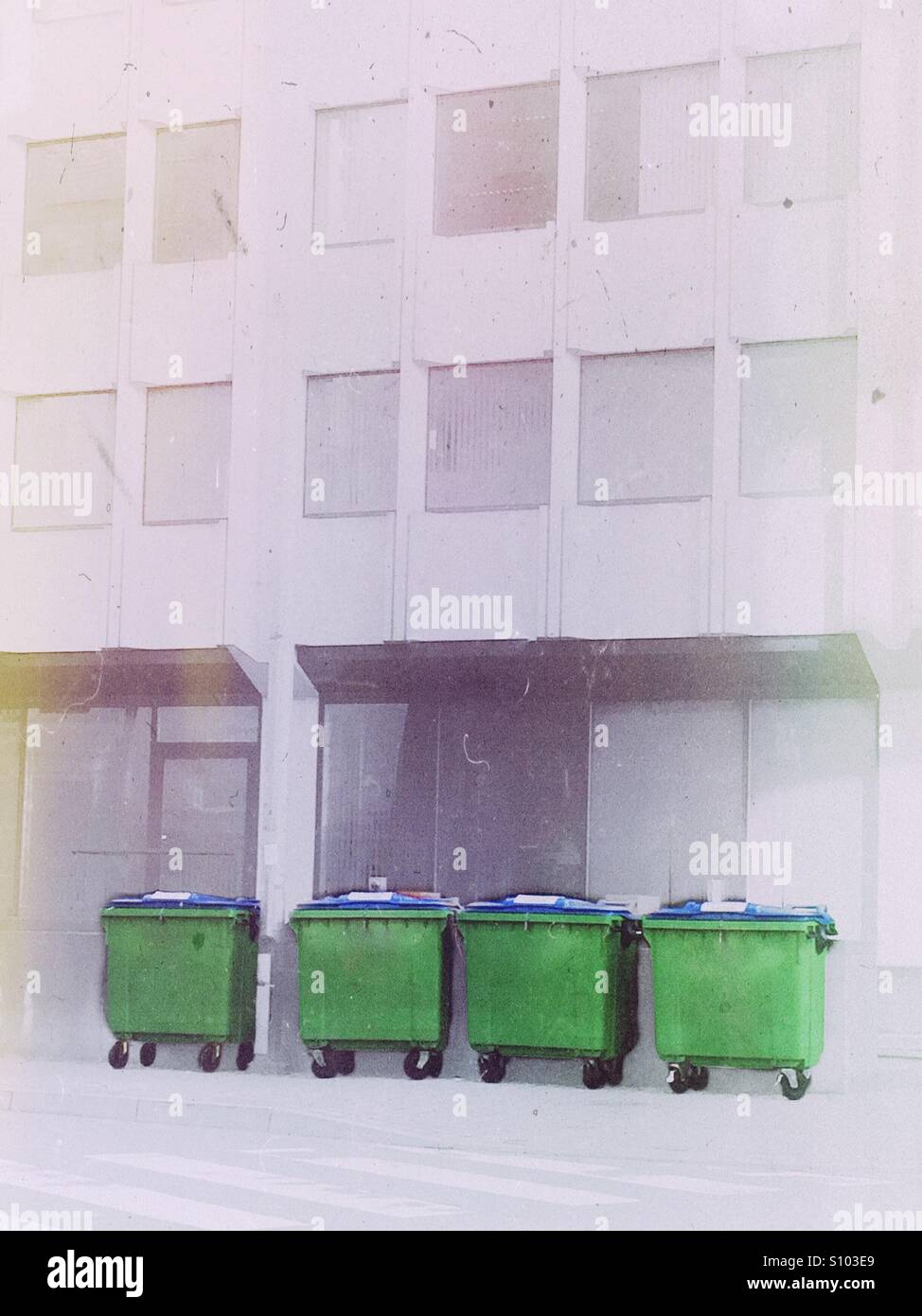 4 contenitori per rifiuti di fronte ad un edificio per uffici - Immagine stock catturata con smartphone