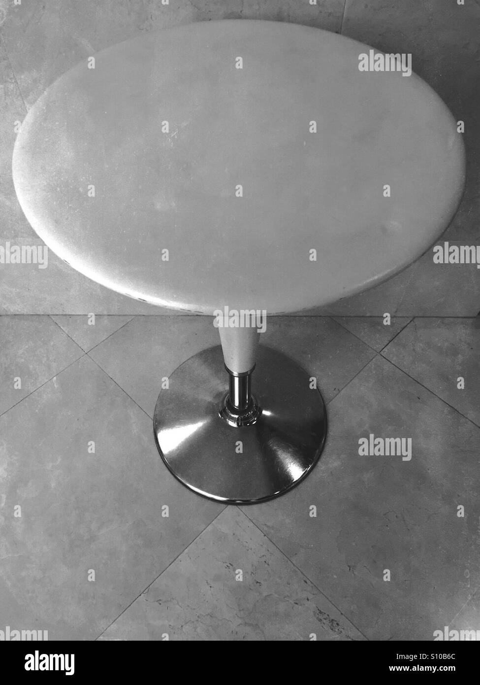 Round vuoto Bombo tabella in piedi su un pavimento piastrellato contro una parete - Immagine stock catturata con smartphone