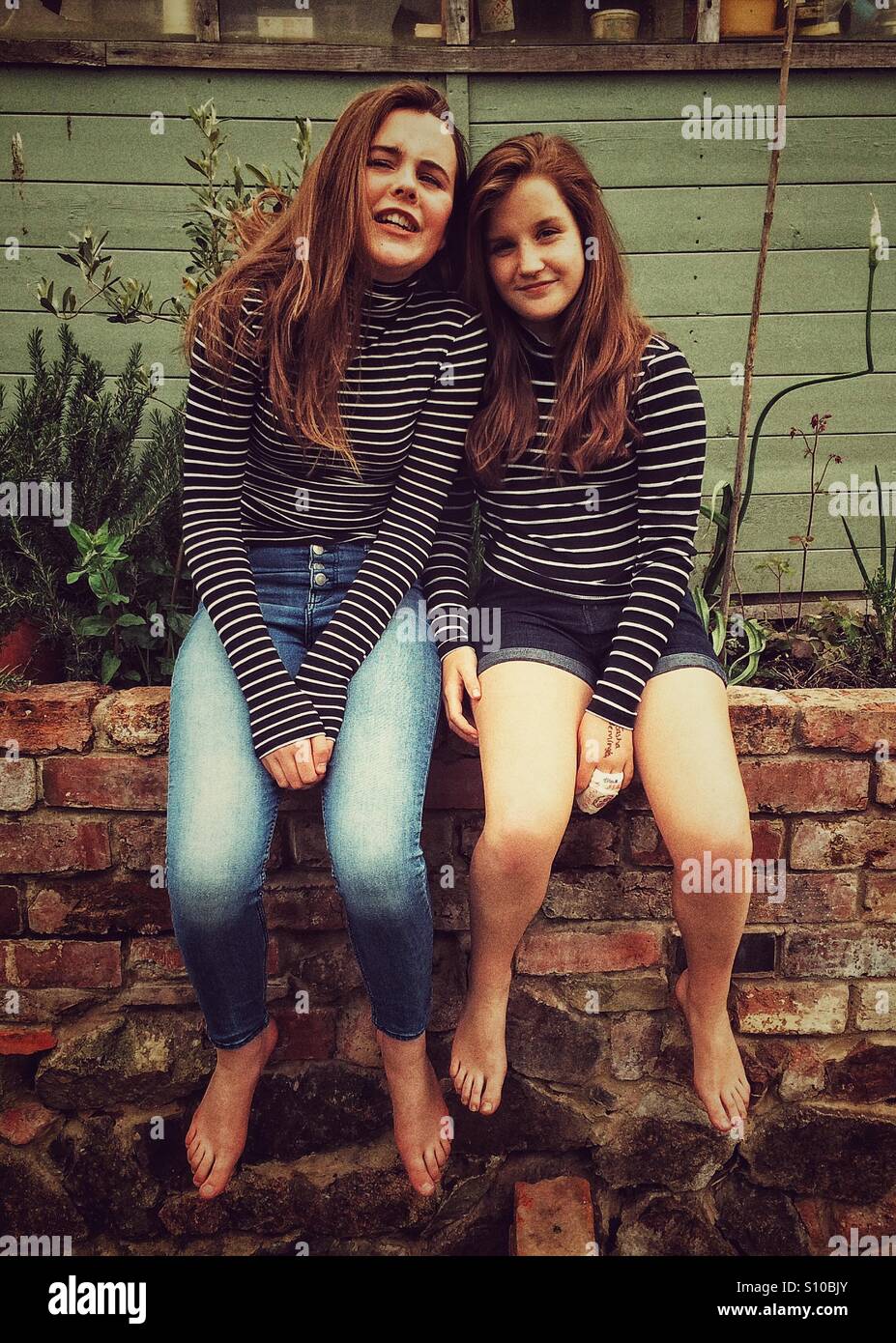 Due ragazze seduto su una parete Foto Stock