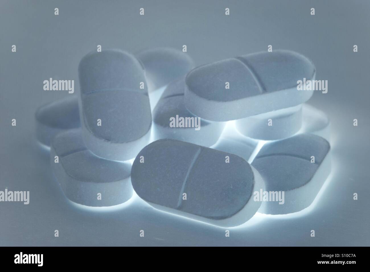 Un mucchio di incandescente pillole, compresse o farmaci su uno sfondo bianco. Luminose compresse antidolorifiche. Foto Stock