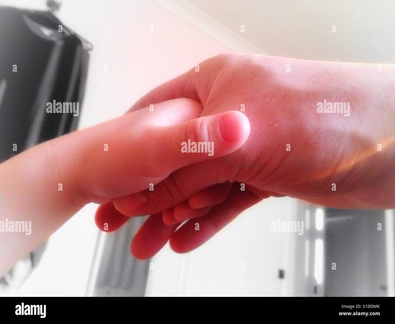 Un giovane bambino è tenuto in mano da un maschio adulto mano. Foto Stock