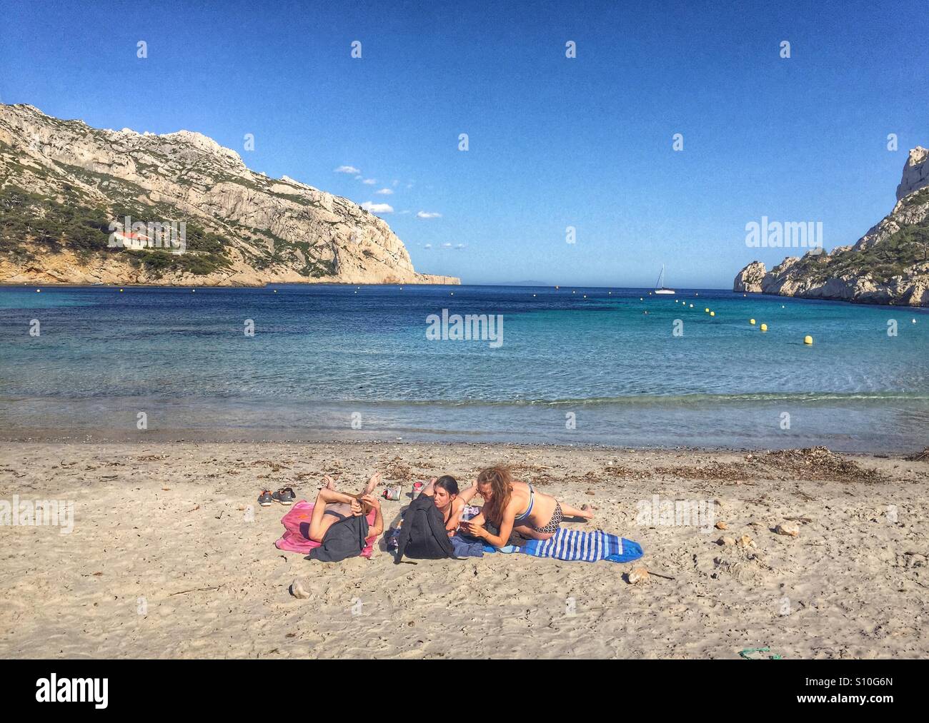 Tre donne a prendere il sole sulla spiaggia les calanques de Marseille FRANCIA Foto Stock