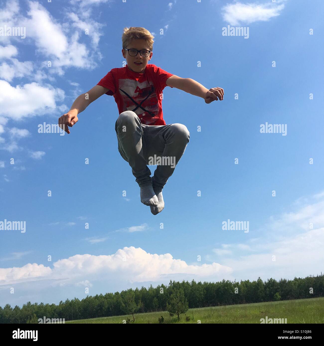 Ragazzo adolescente il salto in aria al di fuori su di un caldo pomeriggio di primavera. Foto Stock