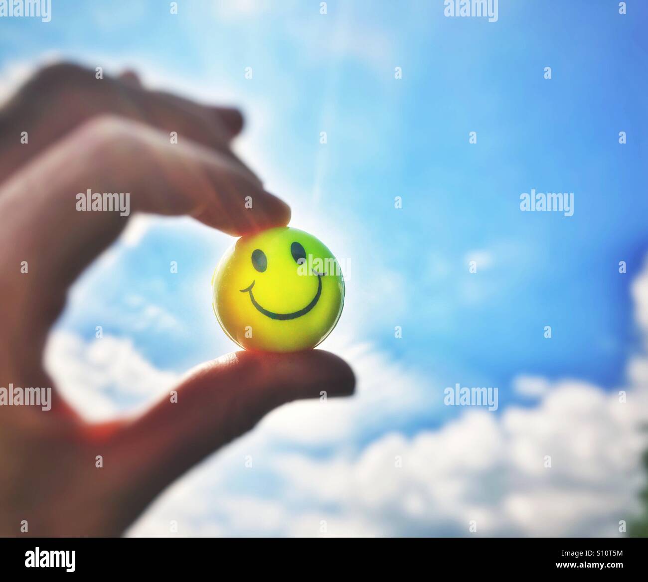 Gli Emoji sulla sfera gialla contro un nuvoloso cielo blu Foto Stock