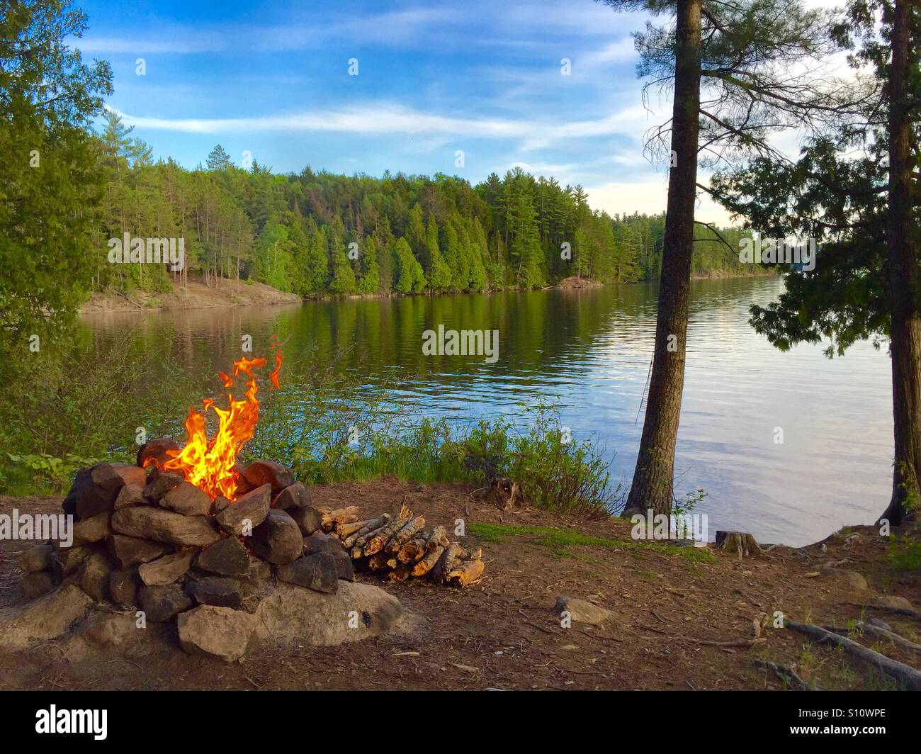 Campfire roccia una buca per il fuoco con le fiamme a Lago di foresta Foto Stock