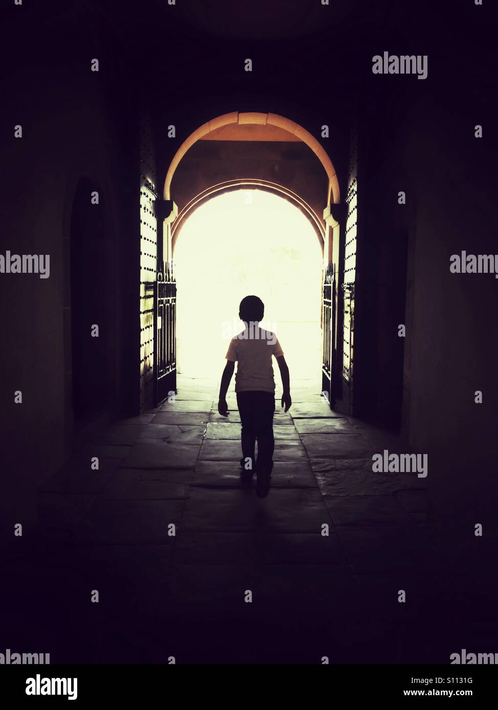 Ragazzo che cammina verso il cancello aperto - Immagine stock catturata con smartphone