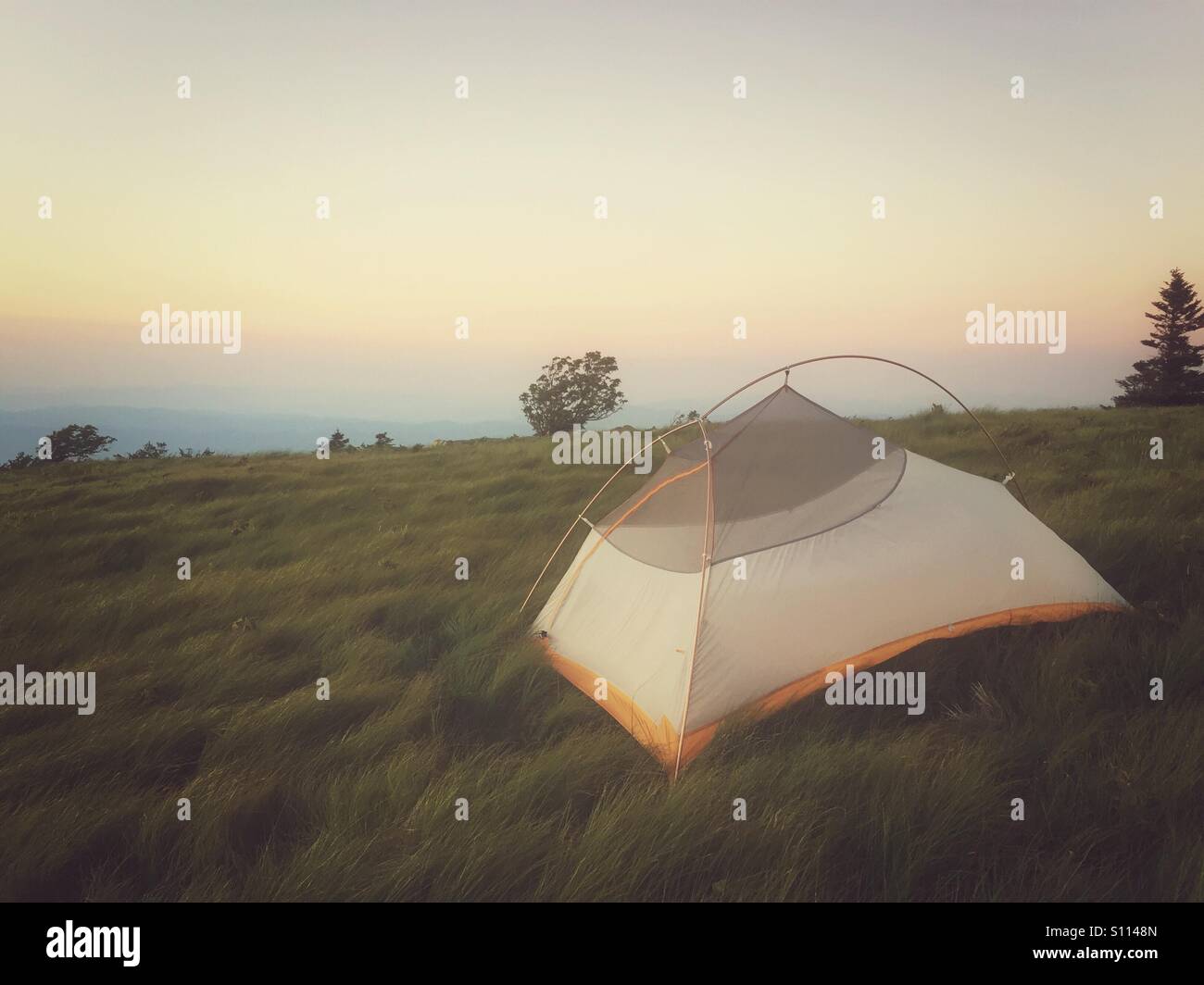 Un camper ha impostato la tenda in un campo al crepuscolo Foto Stock