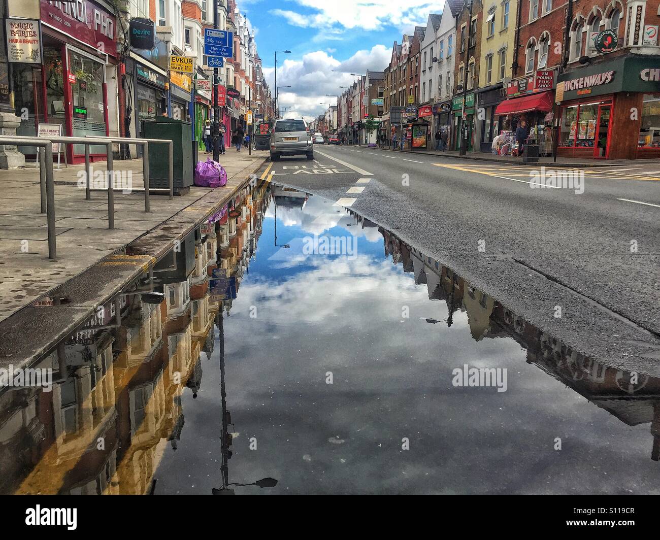 Riflessione urbano dopo la pioggia. Una pozza sul Green Lanes, Harringay, London, Regno Unito Foto Stock