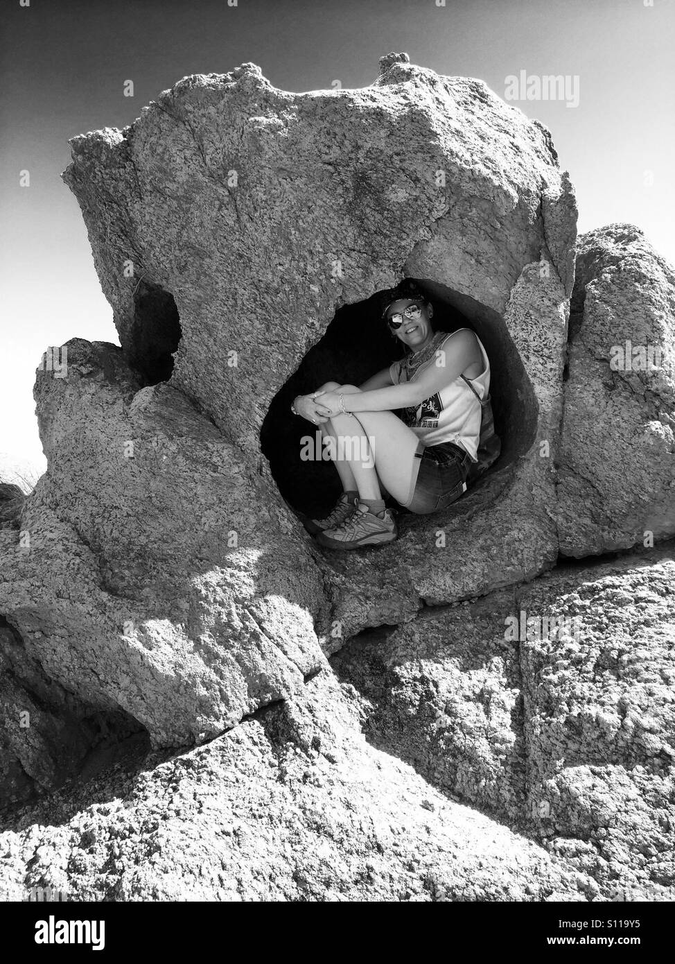 Donna ripara dal sole in una cava di roccia nel deserto di Wadi Rum - Immagine stock catturata con smartphone