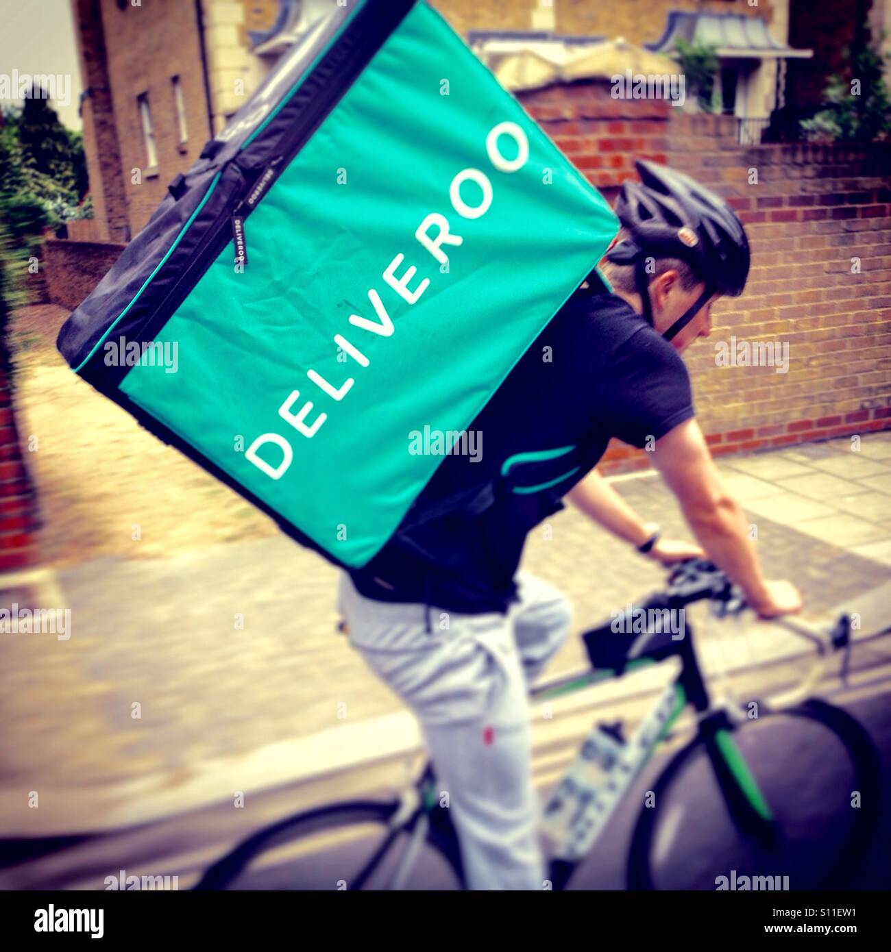 Deliveroo cibo da asporto corriere consegna ciclo pedale / spingere bike ciclista rendendo la consegna di eseguire a Richmond upon Thames. U.K. Foto Stock
