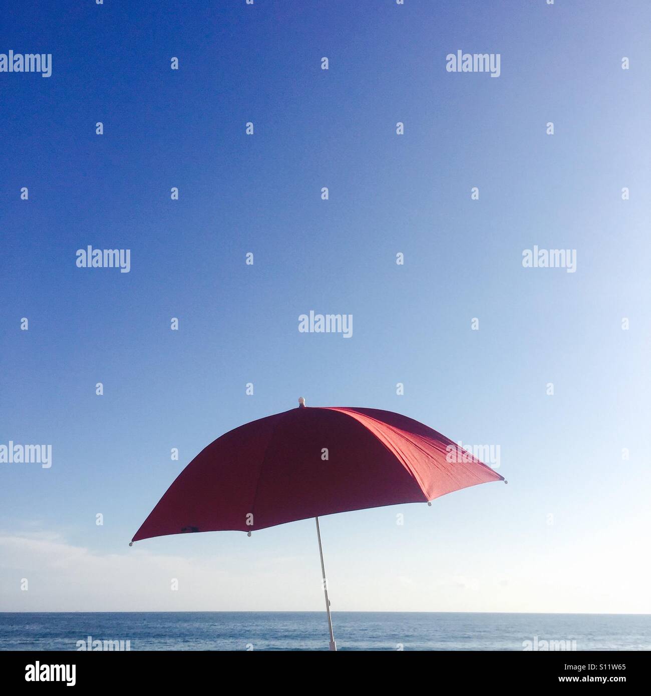Un unico ombrello rosso e l'oceano e cielo. Ventura, California USA. Foto Stock