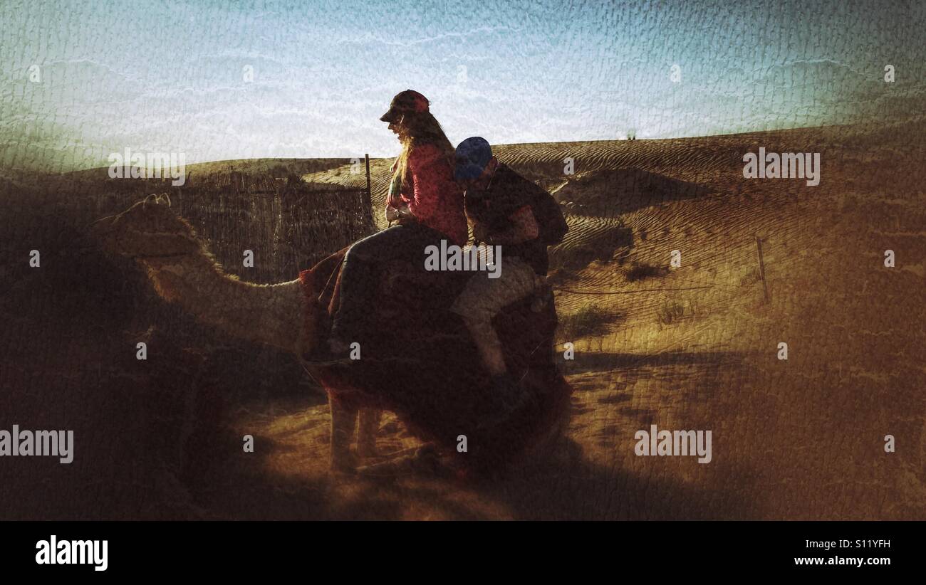 Discendente di cammello sul deserto di sabbia macinata con due piloti su di esso - Immagine stock catturata con smartphone