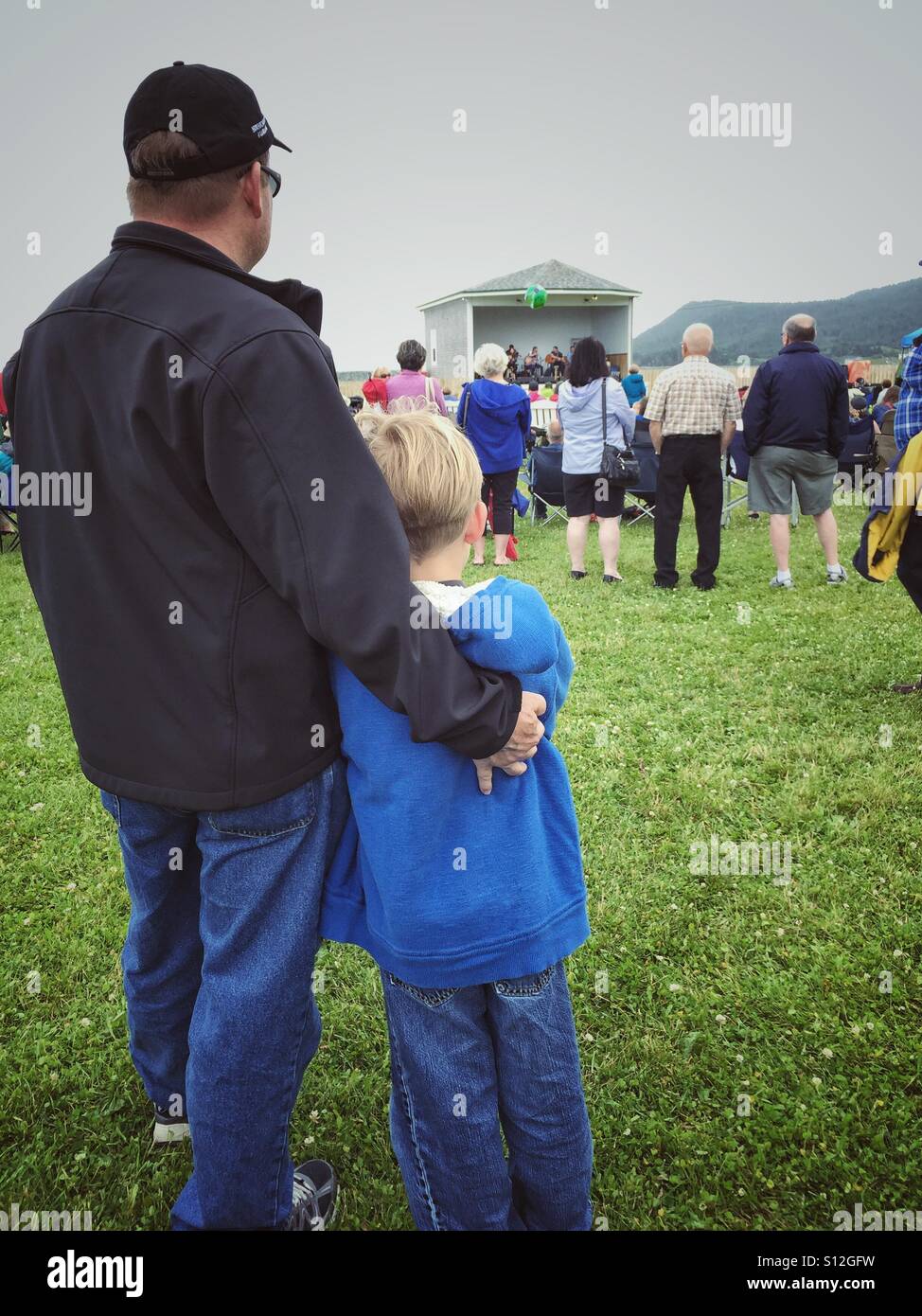 Padre e figlio godetevi l'intrattenimento presso la sponda sud Shamrock Folk Music Festival di Ferryland, Terranova, Canada. - Immagine stock catturata con smartphone