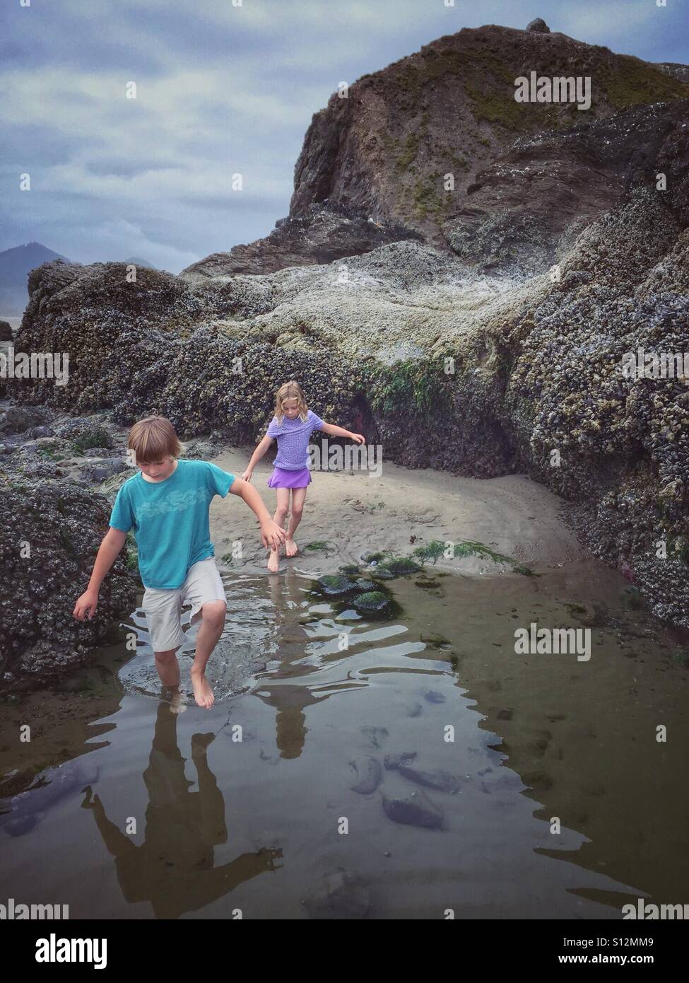Due bambini di esplorare i fondali bassi di Oregon Coast. Foto Stock