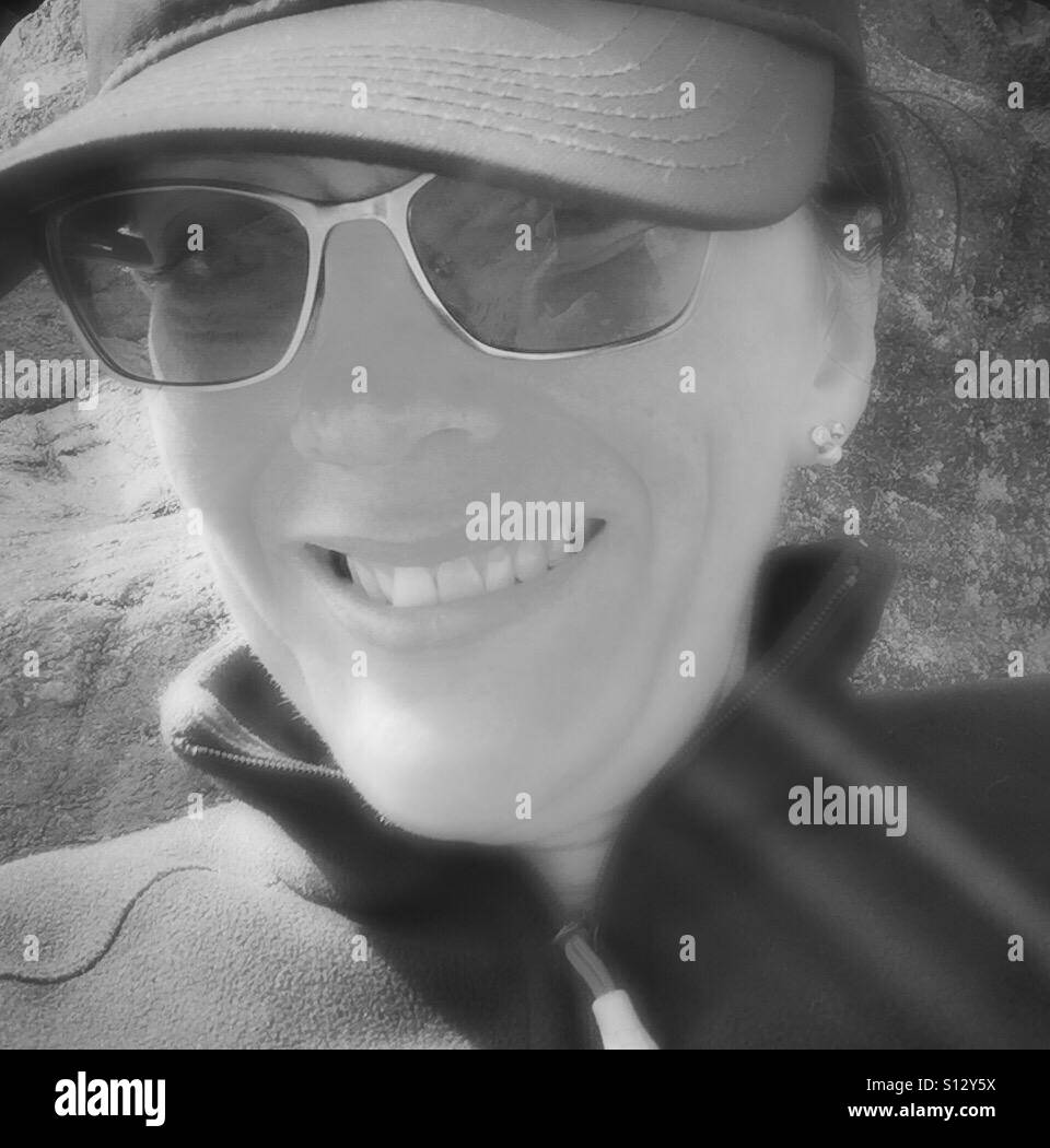 Testa di una donna che indossa gli occhiali da sole e un cappello Foto Stock