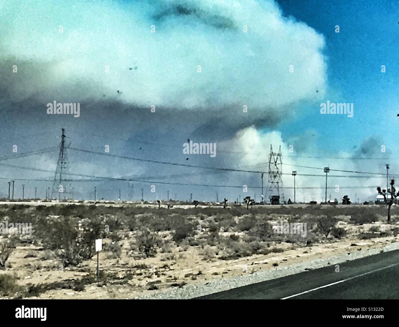 Il fumo dal fuoco soffiando attraverso il cielo su una strada desolata Foto Stock