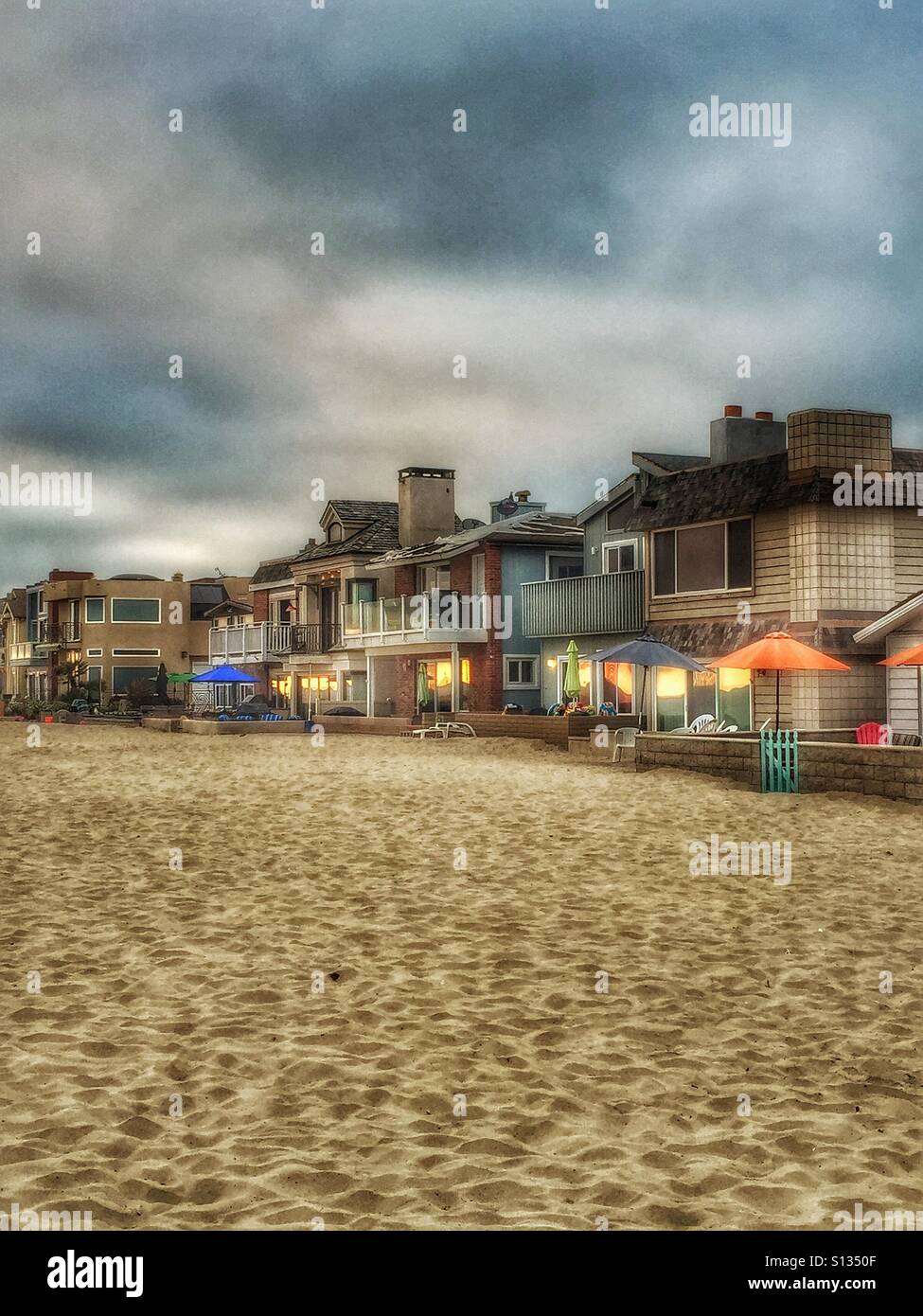 Nuvoloso e piovoso sera sulla spiaggia di Newport Beach in California. Linea di case di sabbia sulla spiaggia costare milioni...imballate in come sardine e molto piccola. Newport Beach vivere. Foto Stock