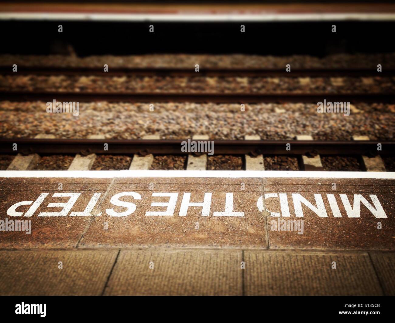Piattaforma della stazione ferroviaria attenzione all'avvertimento gradino. Foto di un telefono cellulare con post-elaborazione di alcuni telefoni o tablet. - Immagine stock catturata con smartphone
